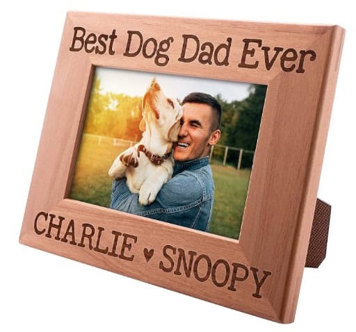 A wooden picture frame showing a picture of a man and a dog with the phrase "Best Dog Dad Ever" on the top and the name of the man and dog on the bottom.